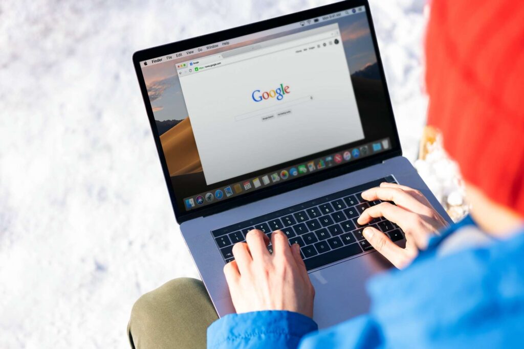 laptop on a desk with a person's hand, representing a mobile-optimized roofing website design for Frisco